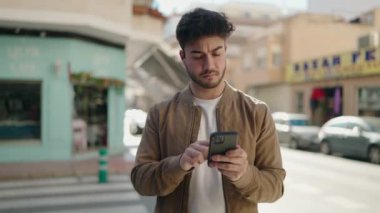 Sokakta akıllı telefon kullanan İspanyol asıllı genç bir adam.