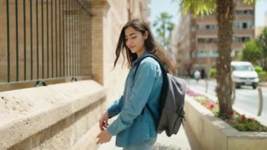 Young hispanic girl student standing with arms crossed gesture at street