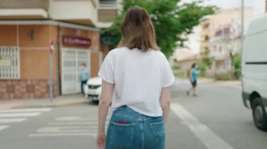 Kendine güvenen genç bir kadın caddede kollarını kavuşturmuş duruyor.