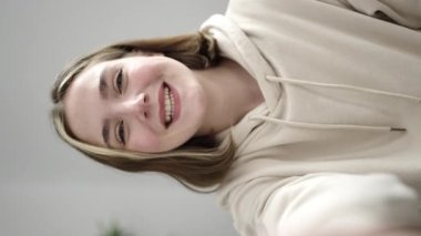 Young blonde woman having video call sitting on sofa at home