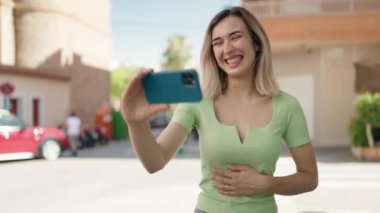 Sokakta akıllı telefondan video seyreden kendine güvenen genç bir kadın.