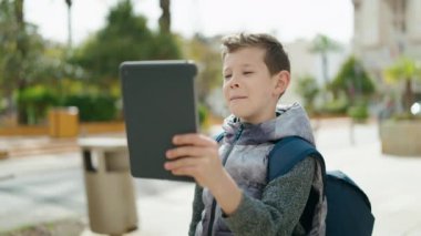 Sarışın çocuk sokakta video görüşmesi yapıyor.
