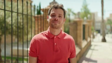 Young hispanic man smiling confident doing photo gesture with hands at street