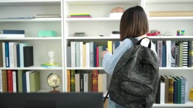 Kütüphane Üniversitesi 'nde akıllı telefondan kitap arayan güzel İspanyol bir kız öğrenci.