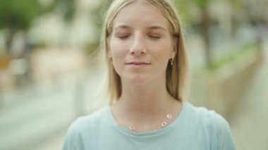 Sokakta kendine güvenen genç sarışın kadın gülümsüyor