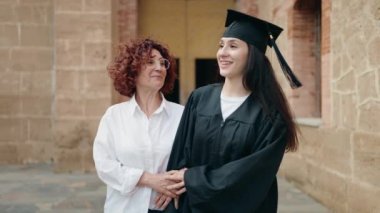 İki kadın anne ve kız mezuniyeti kutluyorlar kampüs üniversitesinde yürüyüş yapıyorlar.