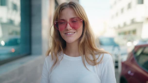 Joven Chica Rubia Sonriendo Confiada Usando Gafas Sol Corazón Calle — Vídeos de Stock