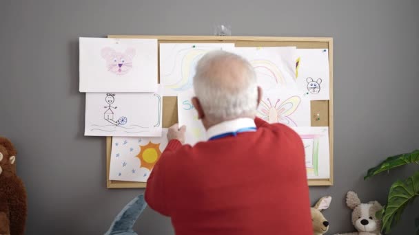 Senior Arbeitet Als Lehrer Und Hängt Zeichnung Korkplatte Kindergarten — Stockvideo