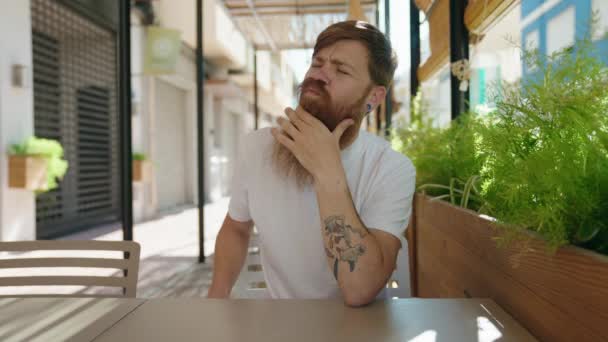 Joven Pelirrojo Sentado Mesa Con Expresión Duda Terraza Cafetería — Vídeo de stock