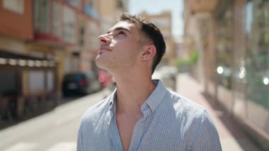 Young hispanic man smiling confident looking to the sky at street