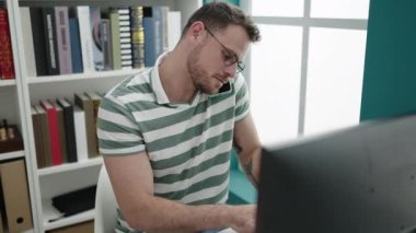 Kütüphanede telefonla konuşan genç beyaz bir adam.