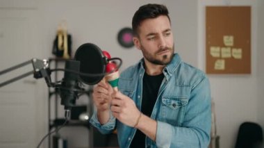 Genç İspanyol adam müzik stüdyosunda marakas çalarak şarkı söylüyor.