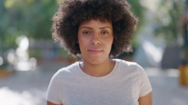 Parkta duran, ciddi ifadeli, Afro-Amerikalı genç bir kadın.