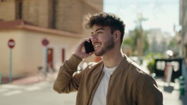 Genç İspanyol adam gülümsüyor. Kendine güveniyor. Sokakta akıllı telefondan konuşuyor.