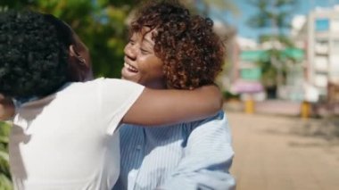 African american women mother and daughter hugging each other at park