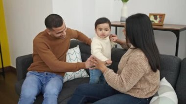 Çift ve oğul evdeki kanepede oturup birbirlerine sarılıyorlar.
