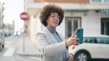 Afro-Amerikalı kadın sokakta akıllı telefon kullanarak kendine güveniyor.