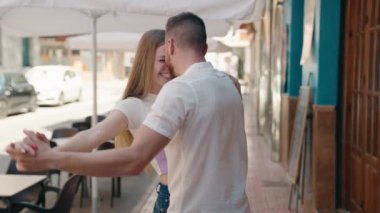 Kadın ve erkek, sokakta dans ederken gülümsüyor.