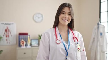Genç, güzel İspanyol kadın doktor gülümsüyor. Kendine güveniyor. Klinikte iyi bir jest yapıyor.