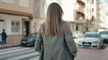 Kendine güvenen genç bir kadın caddede kollarını kavuşturmuş duruyor.