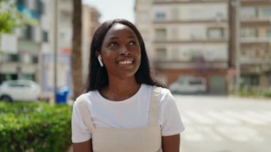 Genç Afrikalı Amerikalı kadın parkta müzik dinliyor.