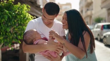 Hispanik aile sokakta öpüşürken birbirlerine sarılıyorlar.