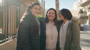 Anne ve kızları gülümsüyor, sokakta birbirlerine sarılıyorlar.