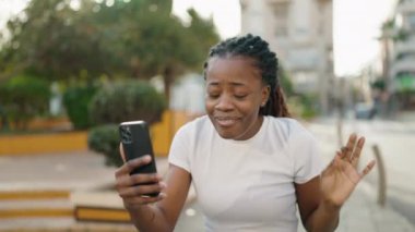 Afro-Amerikalı kadın gülümsüyor. Parkta video araması yaptığından emin.