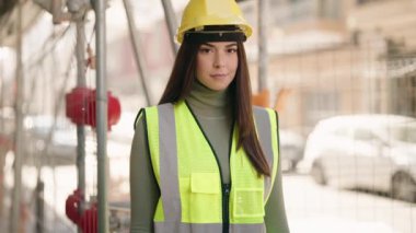 Young hispanic woman architect standing with arms crossed gesture at construction site