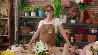 Çiçekçide kendine güvenen orta yaşlı bir çiçekçi.