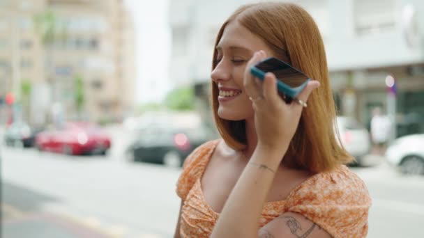 Молодая Рыжая Женщина Улыбается Уверенно Слушая Аудиосообщение Смартфона Улице — стоковое видео
