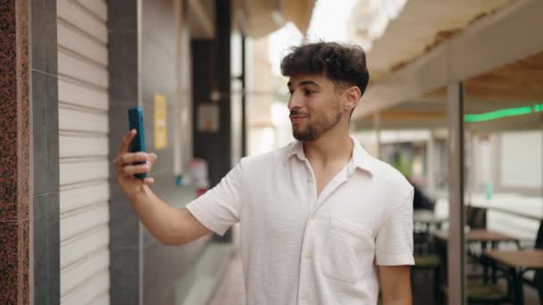 年轻的阿拉伯男子微笑着自信地在街上的智能手机前自拍 — 图库视频影像