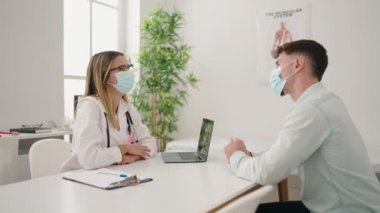 Klinikte tıbbi maske takan genç bir çift doktor ve hasta.