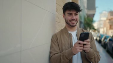 Sokakta akıllı telefon kullanan, kendine güvenen genç bir İspanyol.