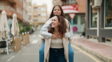 Anne ve kızı sokakta bebekle yürüyor.