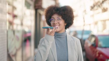 Afro-Amerikalı kadın gülümsüyor. Akıllı telefondan konuşuyor.