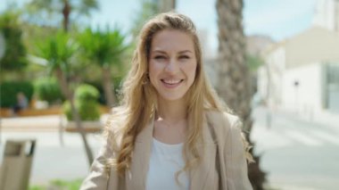 Young blonde woman smiling confident doing photo gesture with hands at park