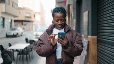 Afro-Amerikalı kadın akıllı telefon kullanıyor.