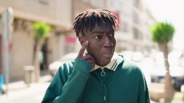 Sokakta şüpheli bir ifadeyle duran Afrikalı Amerikalı bir adam.