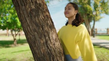 Genç Afrikalı Amerikalı kadın gülümsüyor. Parkta kendine güvenen bir sarılma ağacı.
