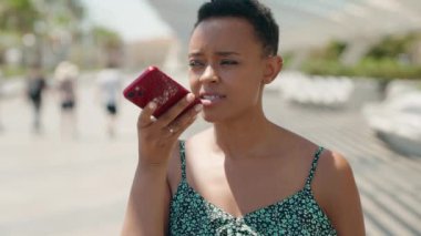 Parkta endişeli bir ifadeyle akıllı telefondan konuşan Afrikalı Amerikalı kadın.