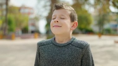 Sarışın çocuk parkta kendinden emin bir şekilde gülümsüyor.