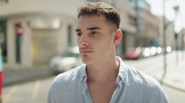 Young hispanic man with relaxed expression standing at street