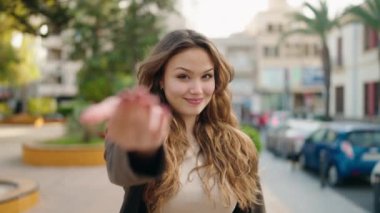 Genç İspanyol kadın gülümsüyor. Kendinden emin. Sokakta el kol hareketi yapıyor.