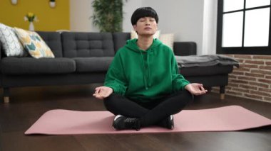 Young chinese woman training yoga exercise sitting on floor at home