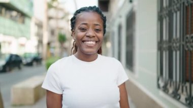 Afro-Amerikalı kadın gülümsüyor. Kendine güveniyor, elleriyle kalp hareketi yapıyor.