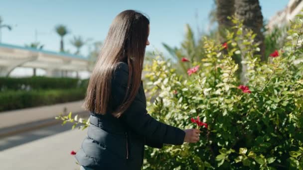 Mujer Joven Sonriendo Confiado Olor Flor Parque — Vídeo de stock