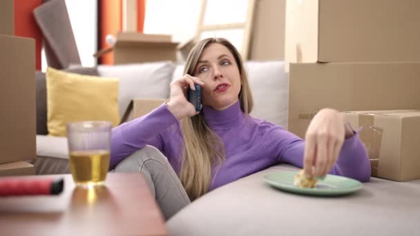 Młoda Blondynka Pomocą Smartfona Jedząc Śniadanie Nowym Domu — Wideo stockowe