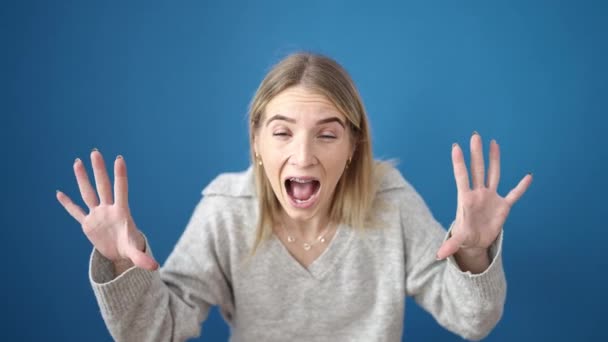 Młoda Blondynka Stojąca Pokrycie Usta Zaskoczony Nad Odizolowanym Niebieskim Tle — Wideo stockowe