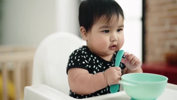 Adorable Hispanic Baby Sitting Highchair Holding Spoon Home — Vídeo de stock
